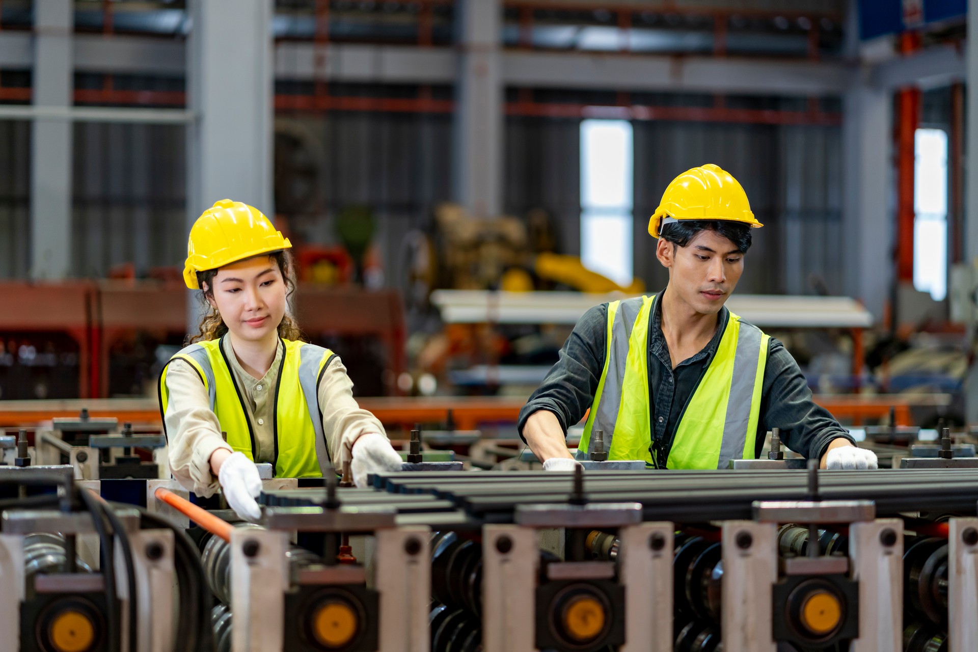 Team of Asian industrial worker is checking the setup value of metal sheet roll forming machine inside roof factory for safety industry construction concept